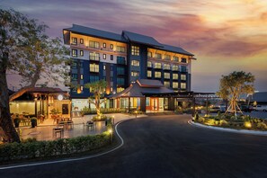 A multi-story hotel with a modern design, featuring a covered outdoor seating area and a parking lot. - The Horizon Groove Hotel (Phitsanulok)