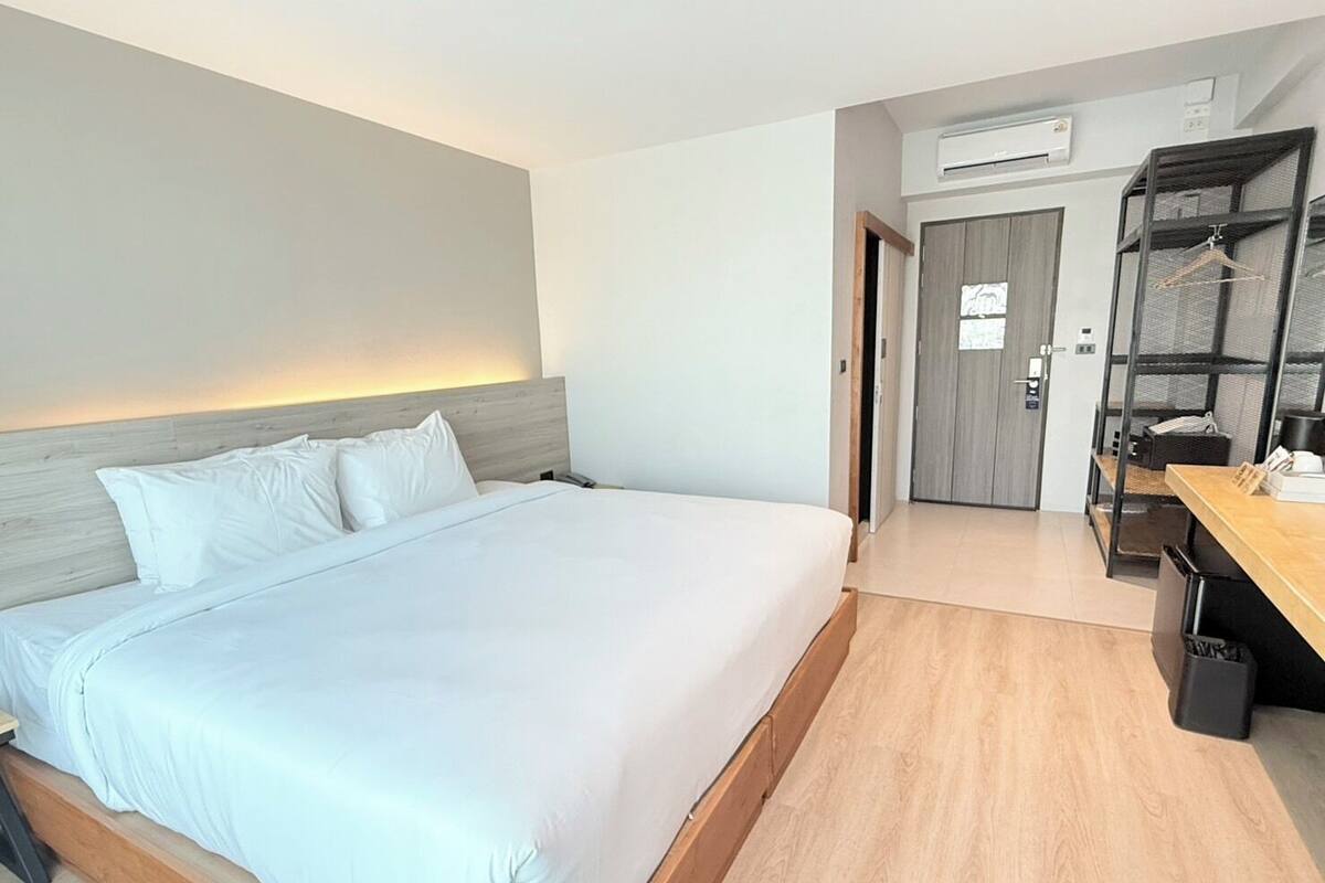 Een hotelkamer met een groot bed, een bureau, een kledingkast en een airconditioner.