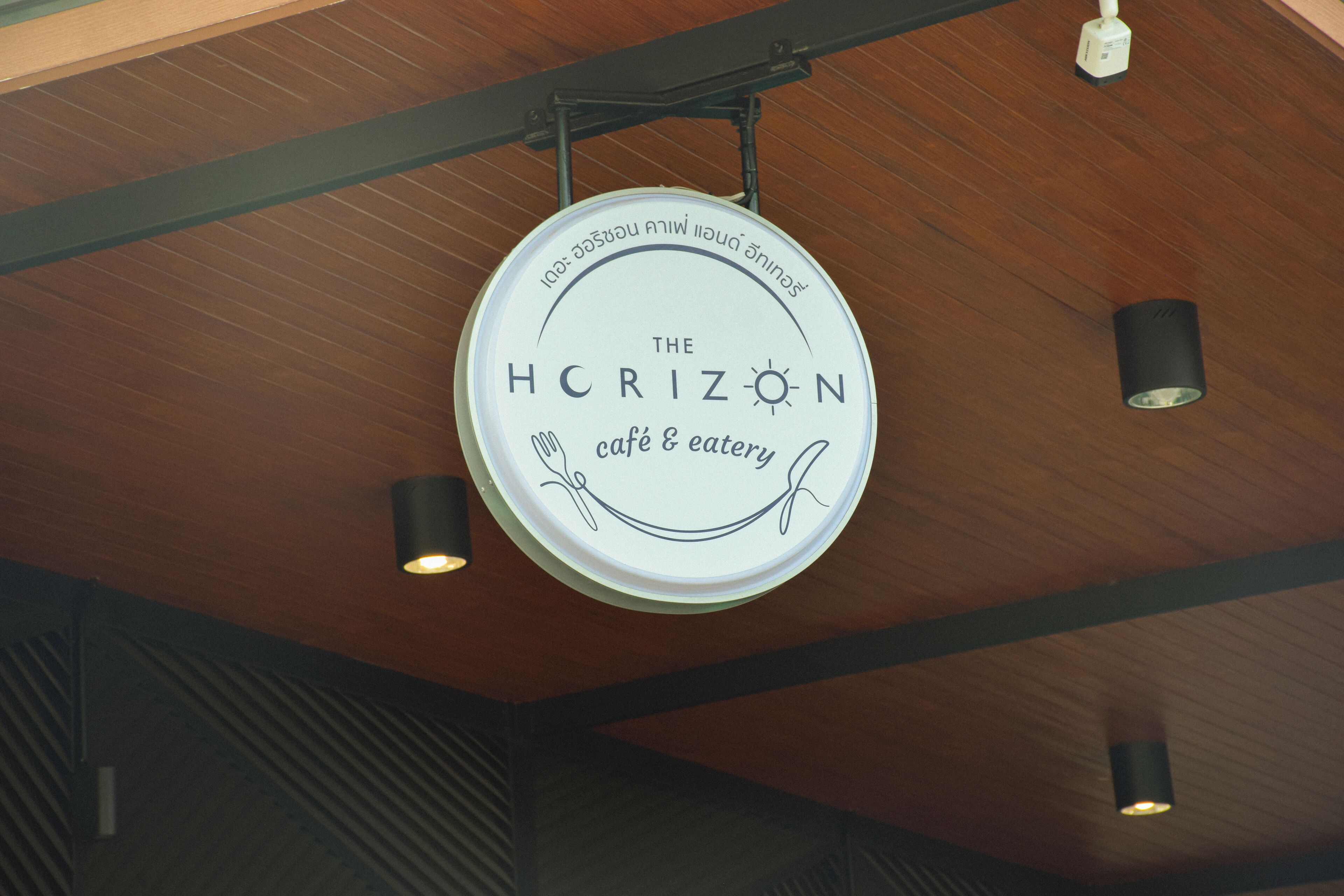 A circular sign with the text "The Horizon café & eatery" hanging from the ceiling.