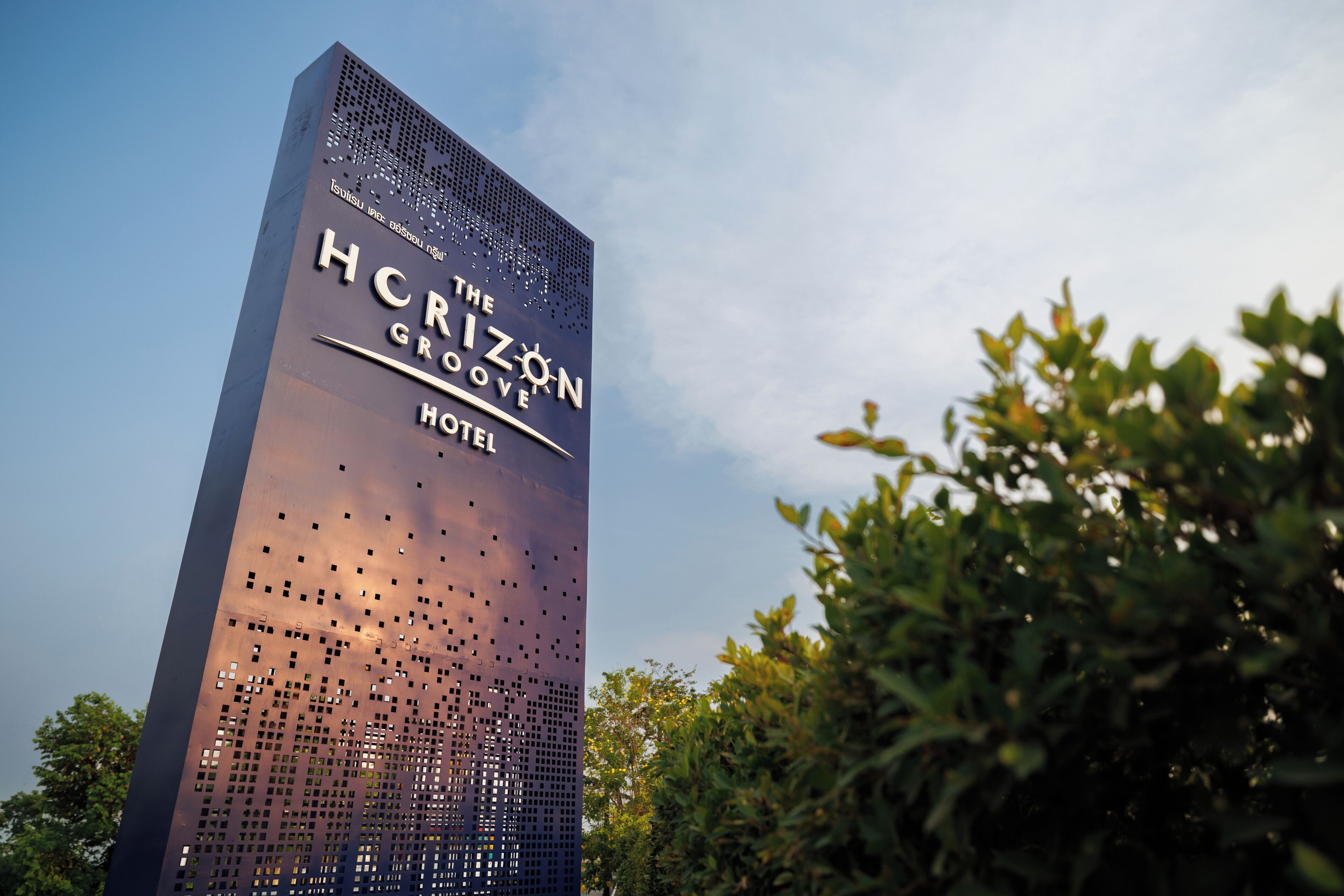 Ein hohes Gebäude mit einer perforierten Fassade und der Beschriftung "The Horizon Grove Hotel".