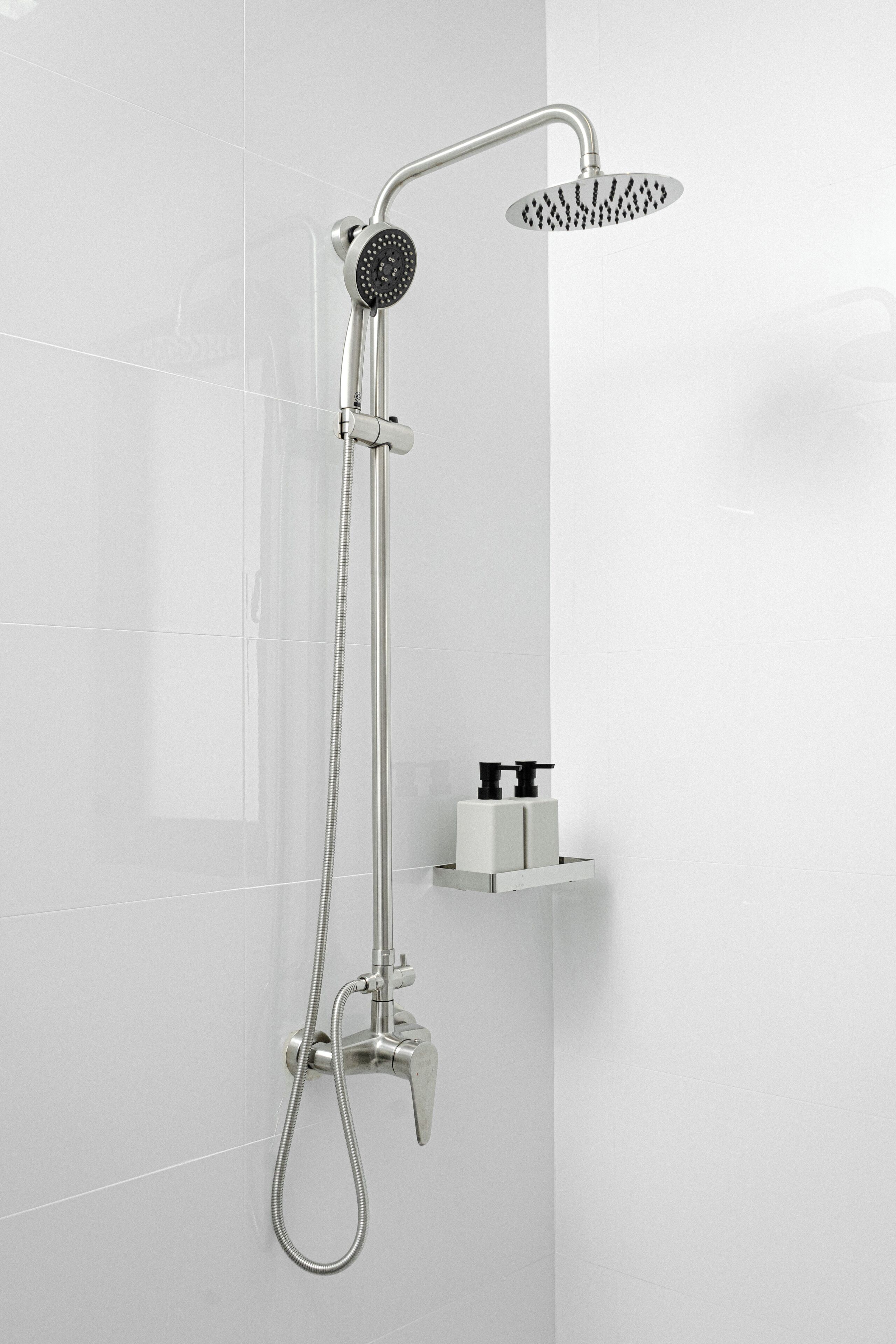 A modern shower with a handheld showerhead and a fixed showerhead, mounted on a wall.