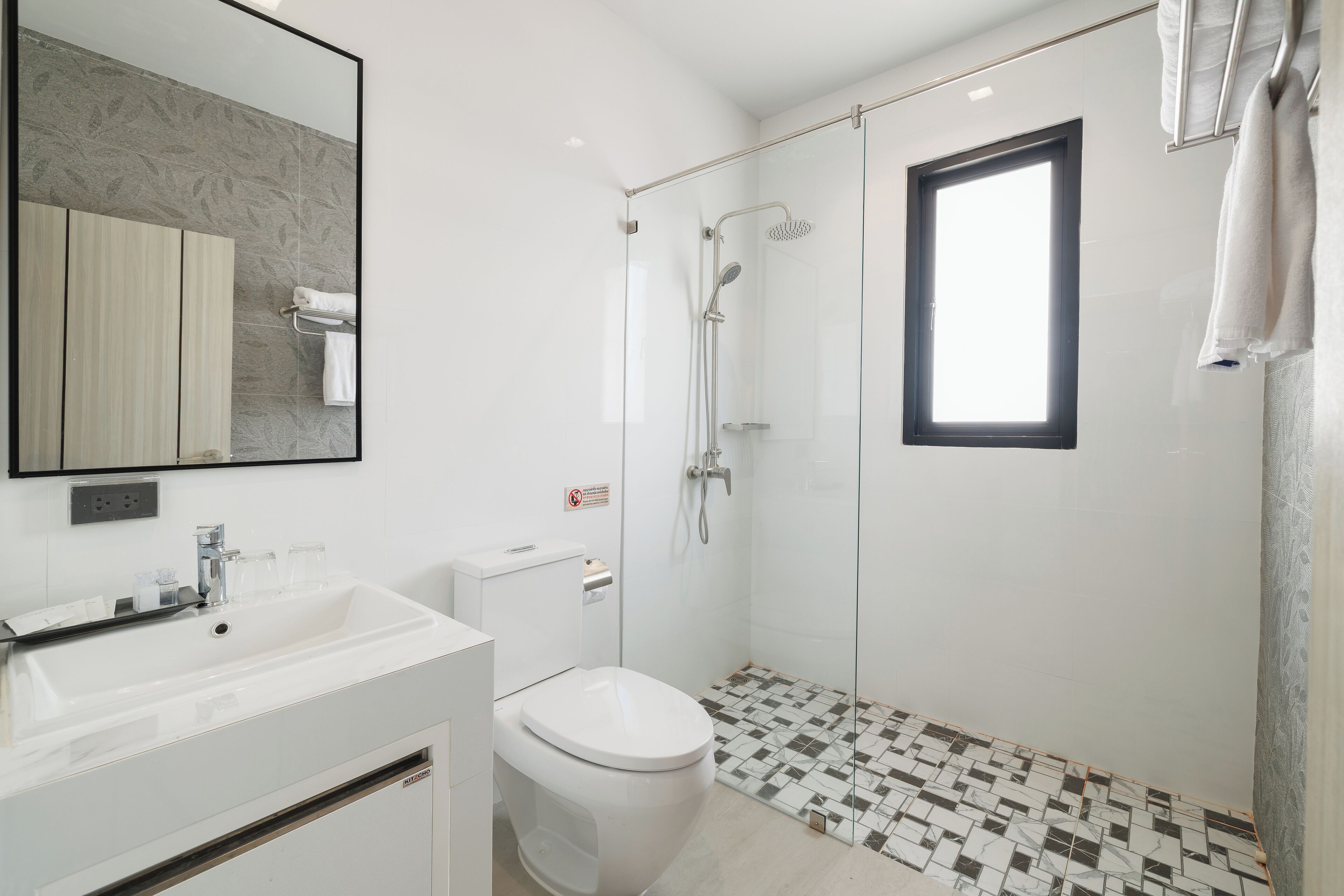 A modern bathroom with a white sink, toilet, and shower area.