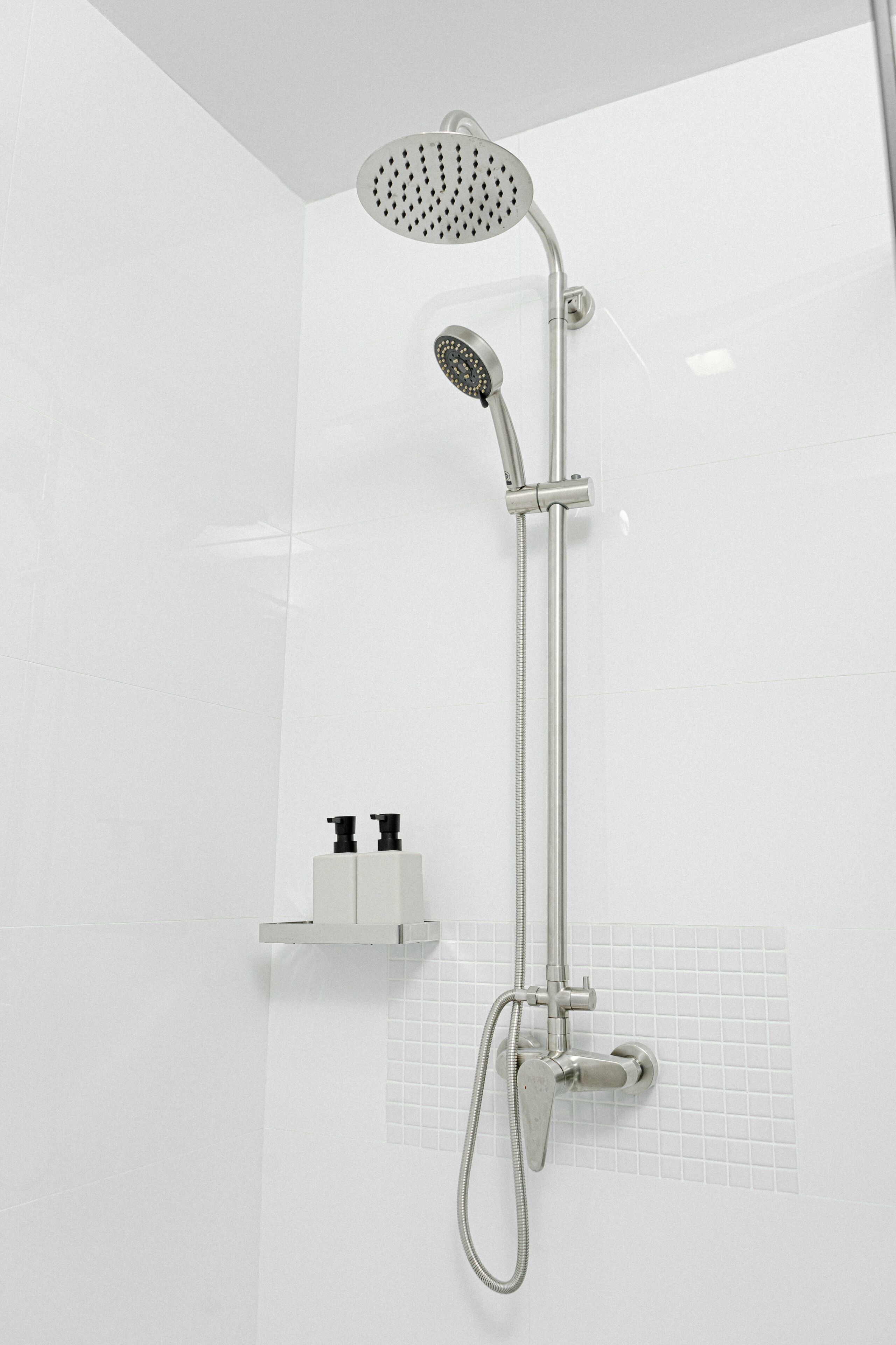 A modern shower with a handheld showerhead and a fixed showerhead.