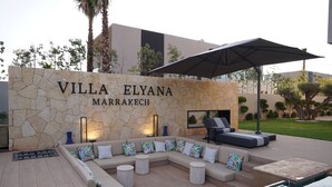 A villa with a stone wall, outdoor seating, and a pool.