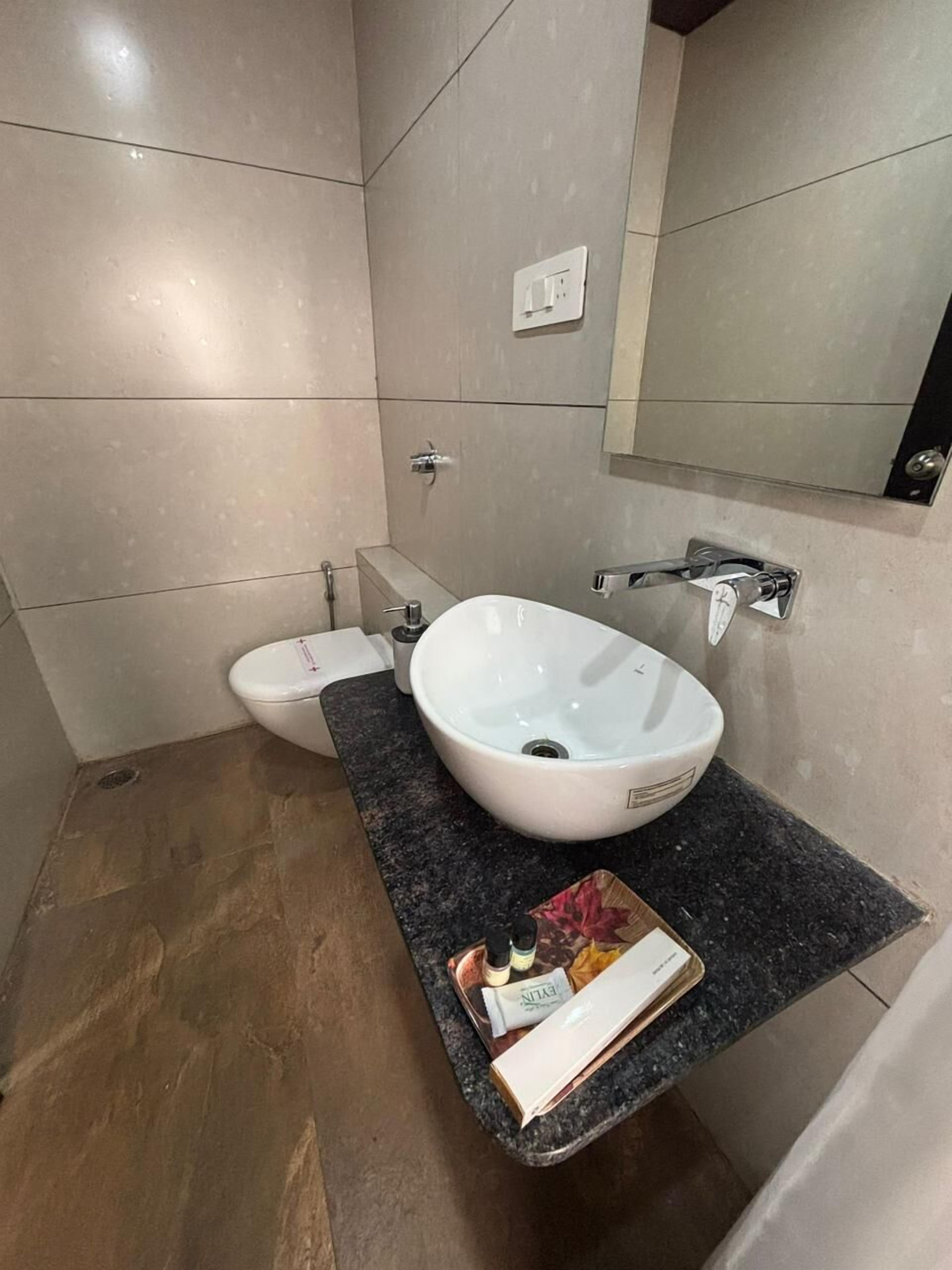 Un baño moderno con un lavamanos blanco, un inodoro y un espejo.