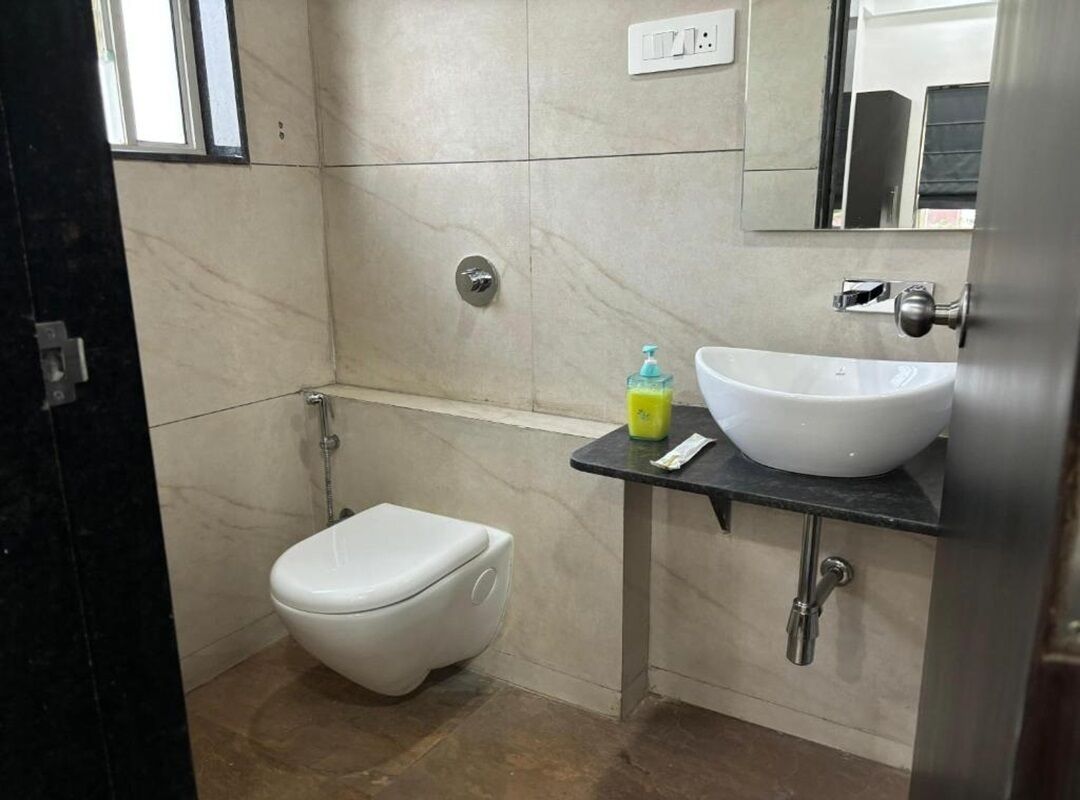 A bathroom with a toilet, a sink, and a mirror.