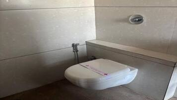 Un baño pequeño y moderno con inodoro blanco, ducha y lavamanos.