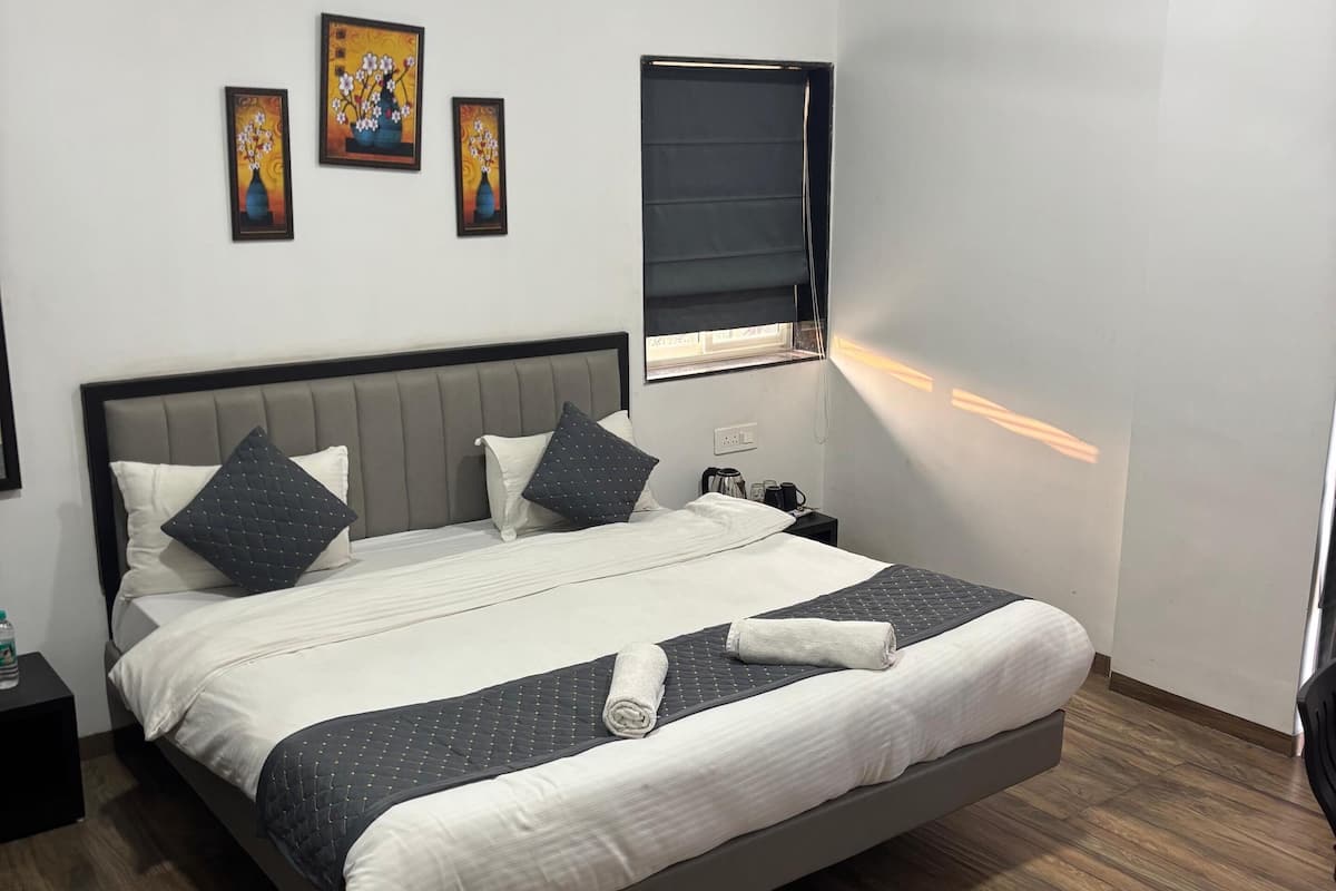 A neatly made bed with a grey headboard, a ceiling fan, and a window with a blind.