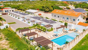 A resort with a swimming pool, sun loungers, a water slide, and solar panels.