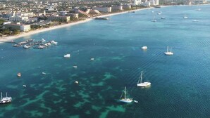 An aerial view of a coastal city with a marina, buildings, and a beach.