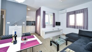 A modern apartment with a dining area, kitchen, living room, and a TV mounted on the wall. - Nice apartment in Rogoznica with sauna (Rogoznica)
