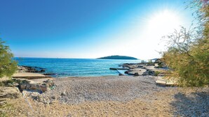 A rocky beach with clear blue sea and a distant island. - Nice apartment in Rogoznica with sauna (Rogoznica)