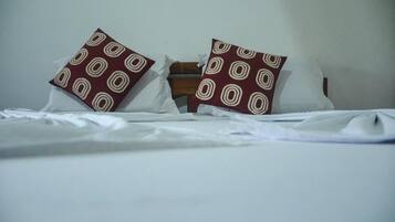 A bed with white linens and two pillows with a circular pattern.