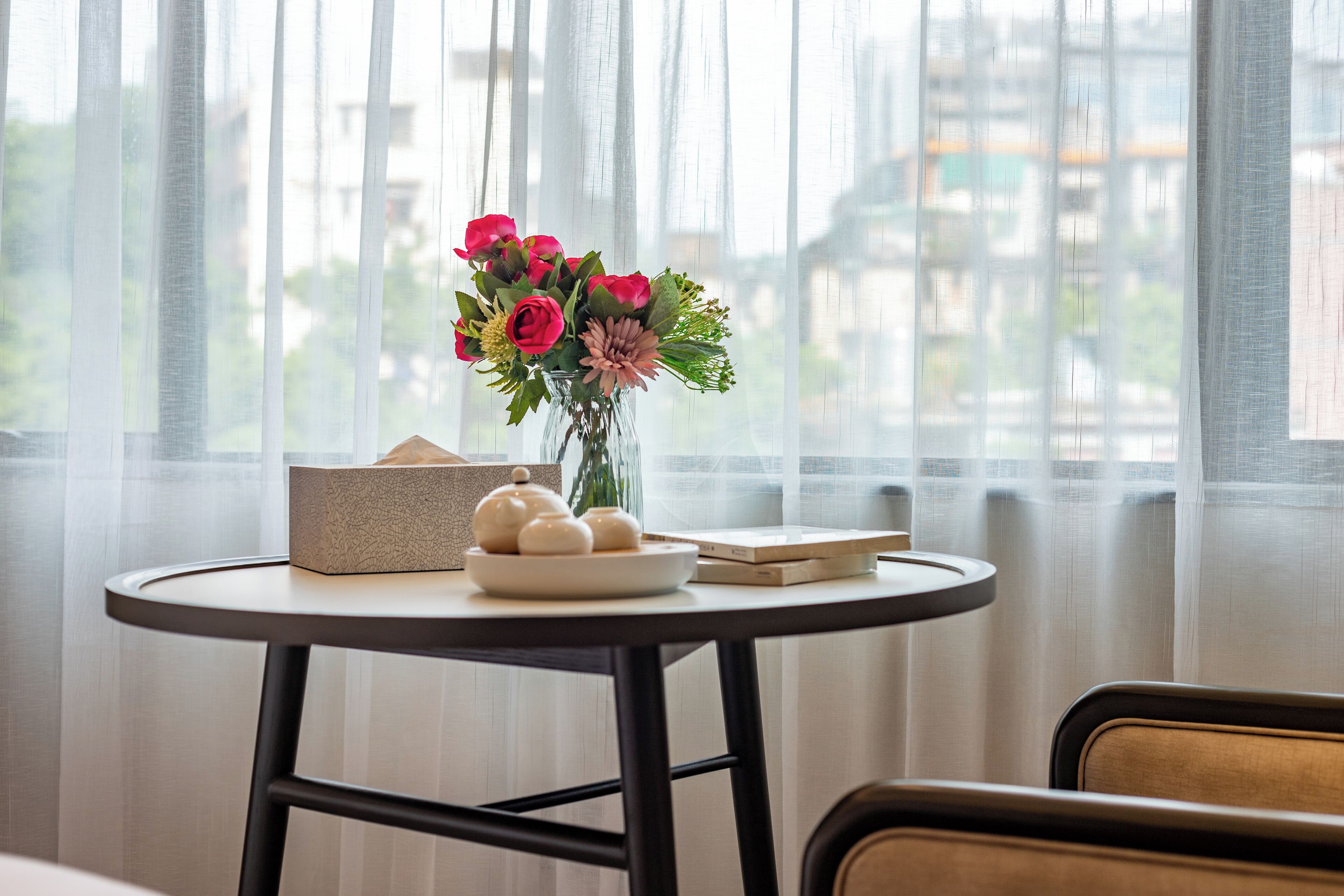 Une table ronde ornée d’un vase de fleurs, d’une boîte et d’une assiette sur laquelle sont posées des théières.
