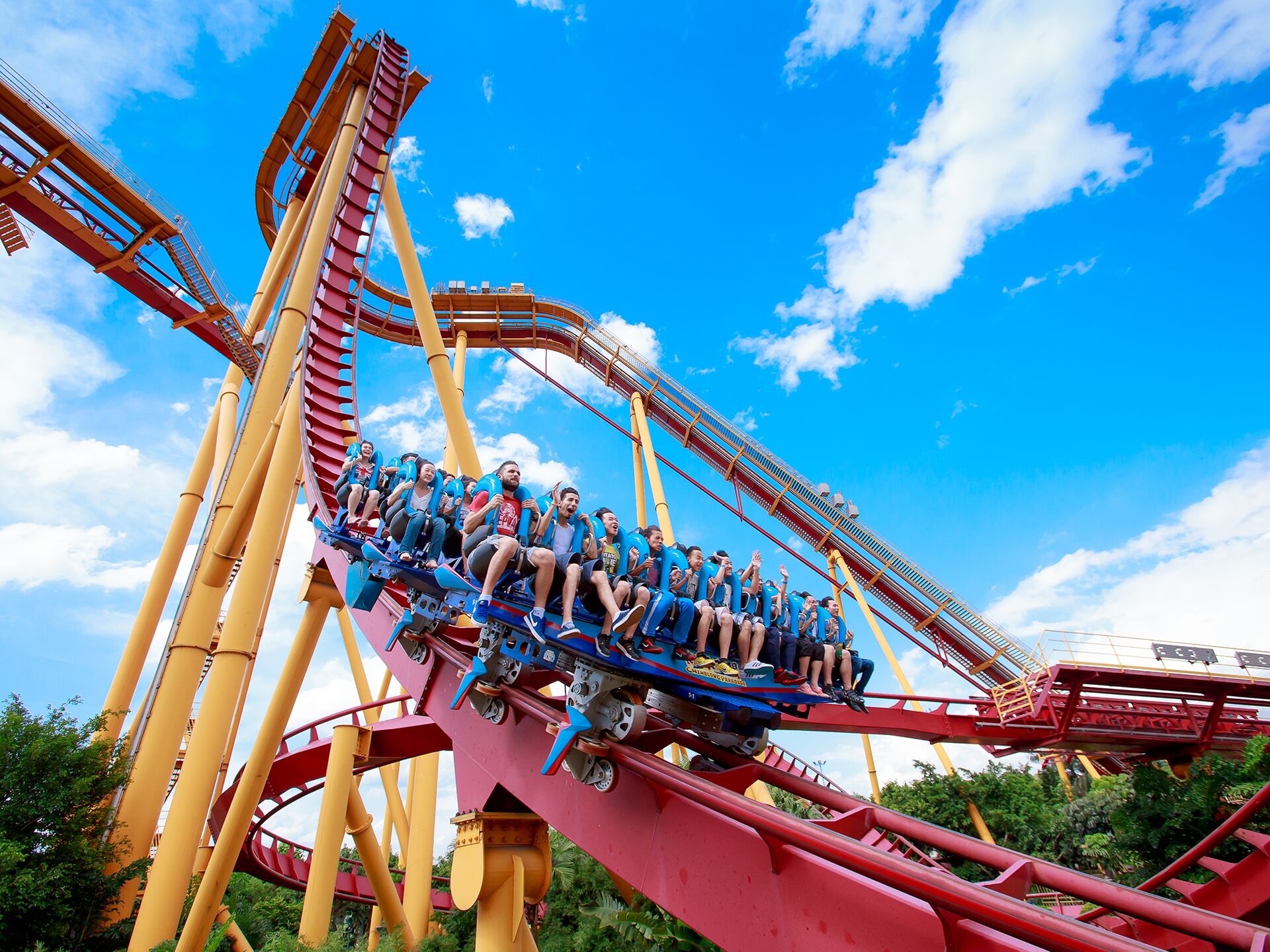 A roller coaster with passengers seated on the track, surrounded by structural supports and under a clear sky.