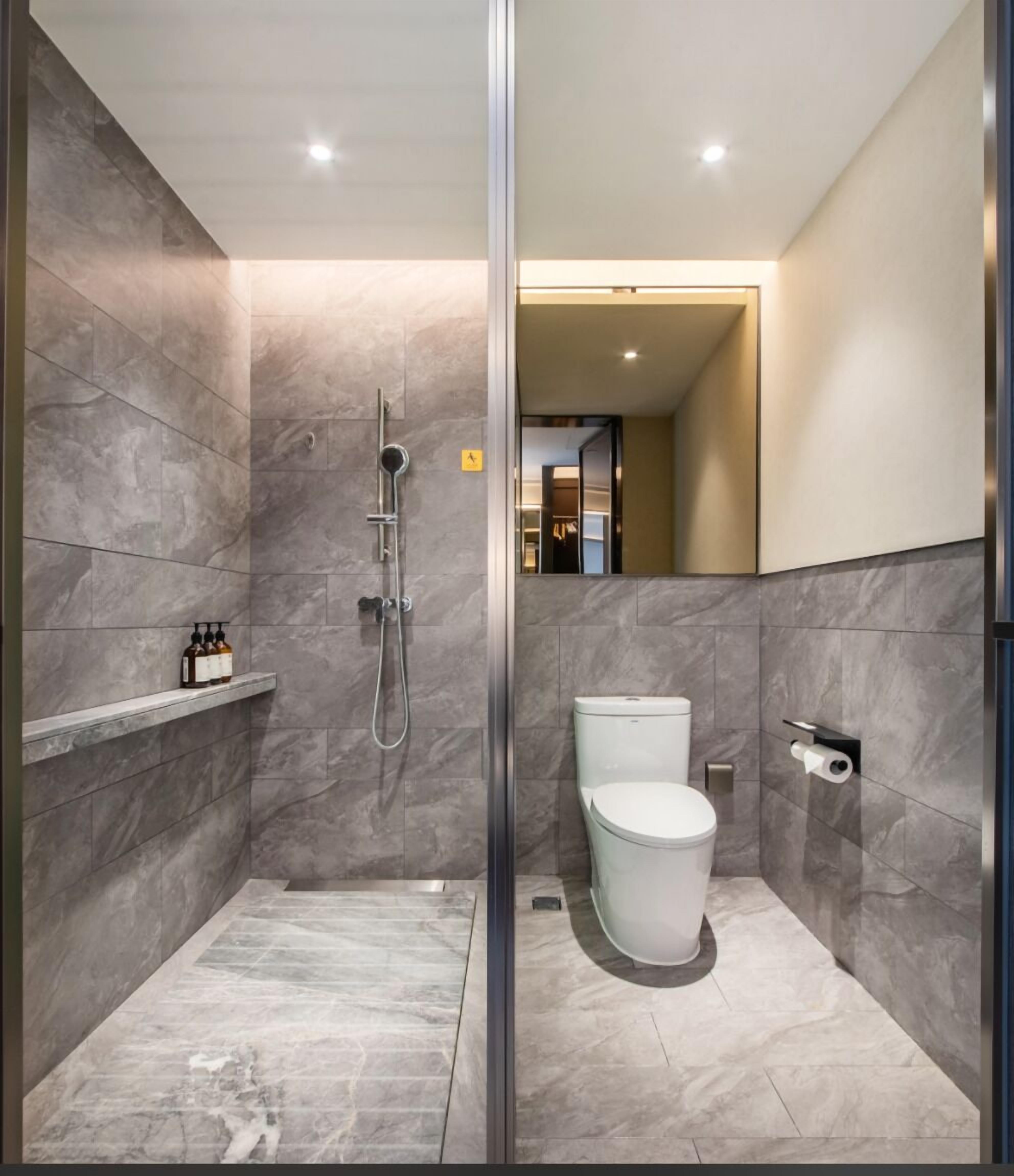 Une salle de bain moderne avec une douche à parois de verre, des toilettes et une étagère contenant des articles de toilette.