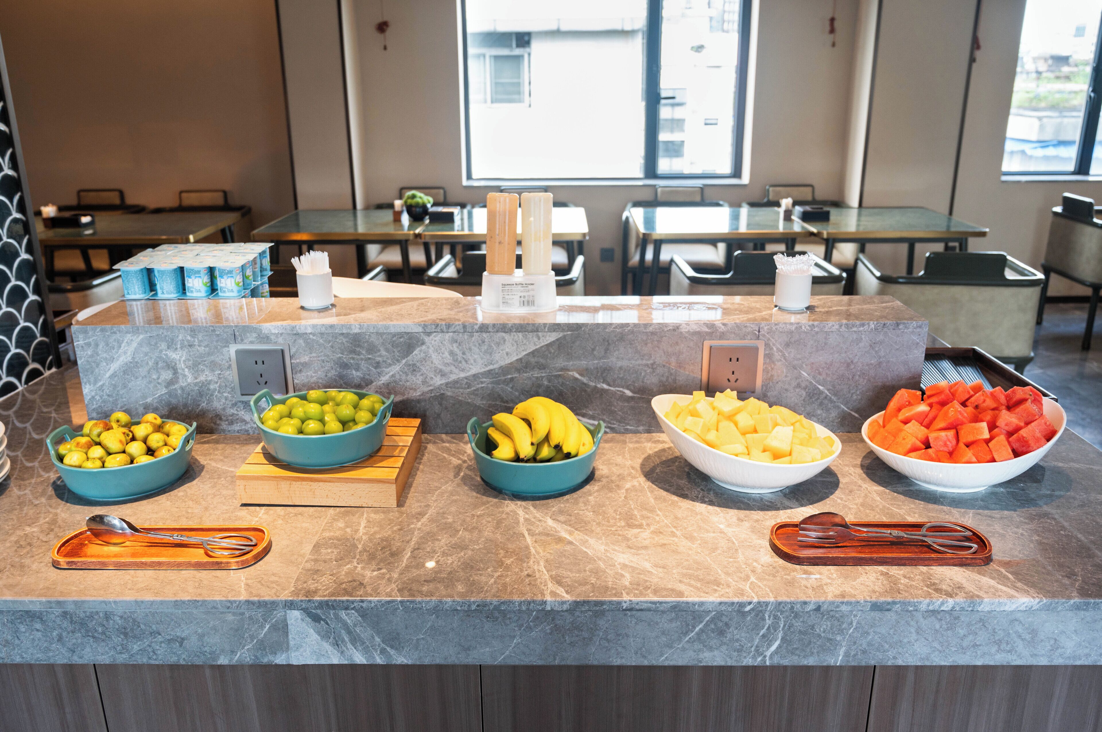 Um balcão de buffet com diversas frutas e acompanhamentos.
