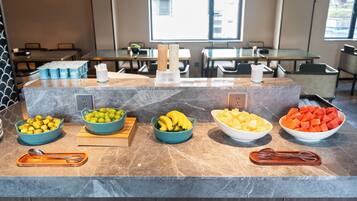 Um balcão de buffet com diversas frutas e acompanhamentos.