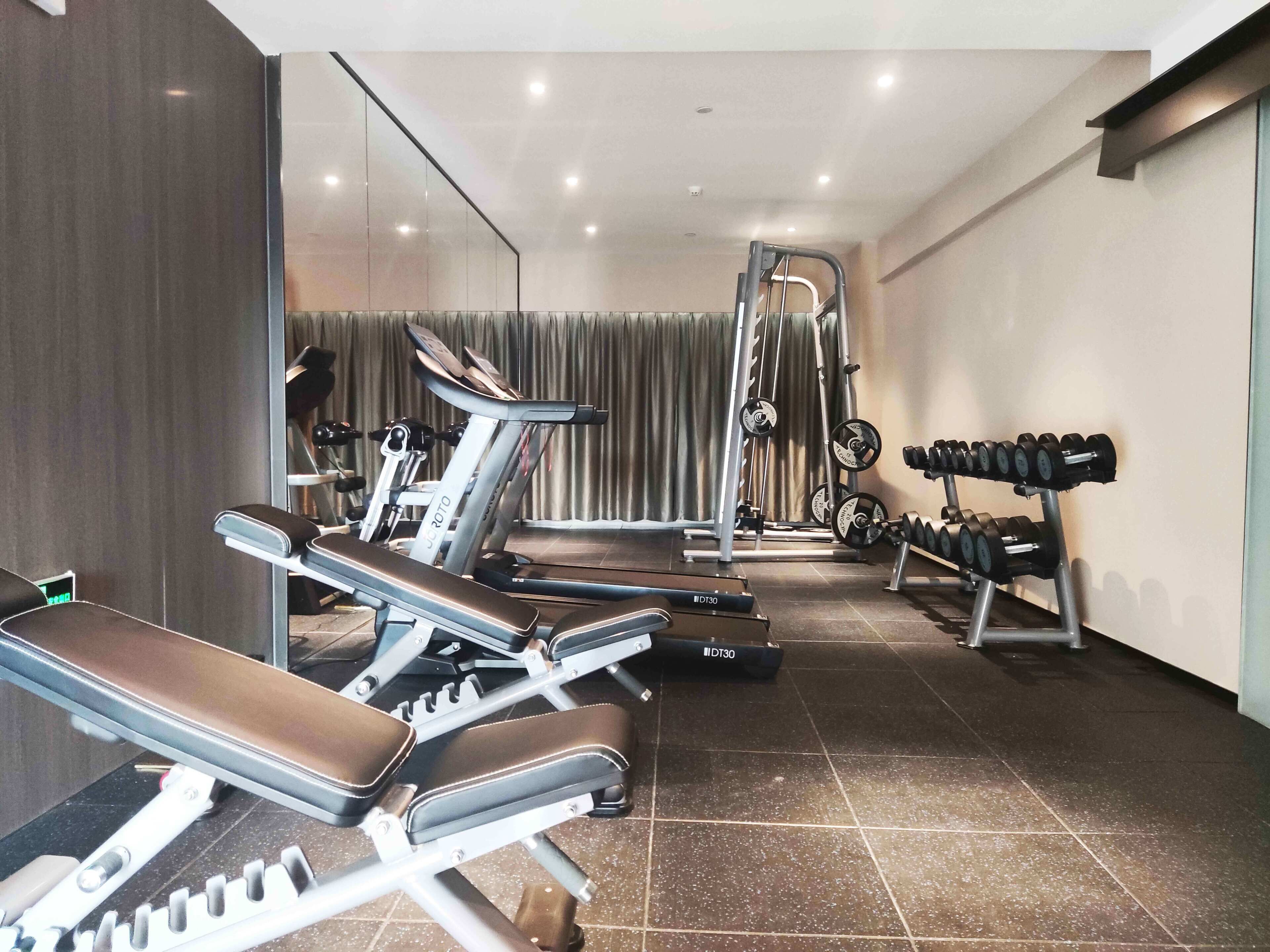 A modern gym with exercise equipment including treadmills, weight benches, and a squat rack.