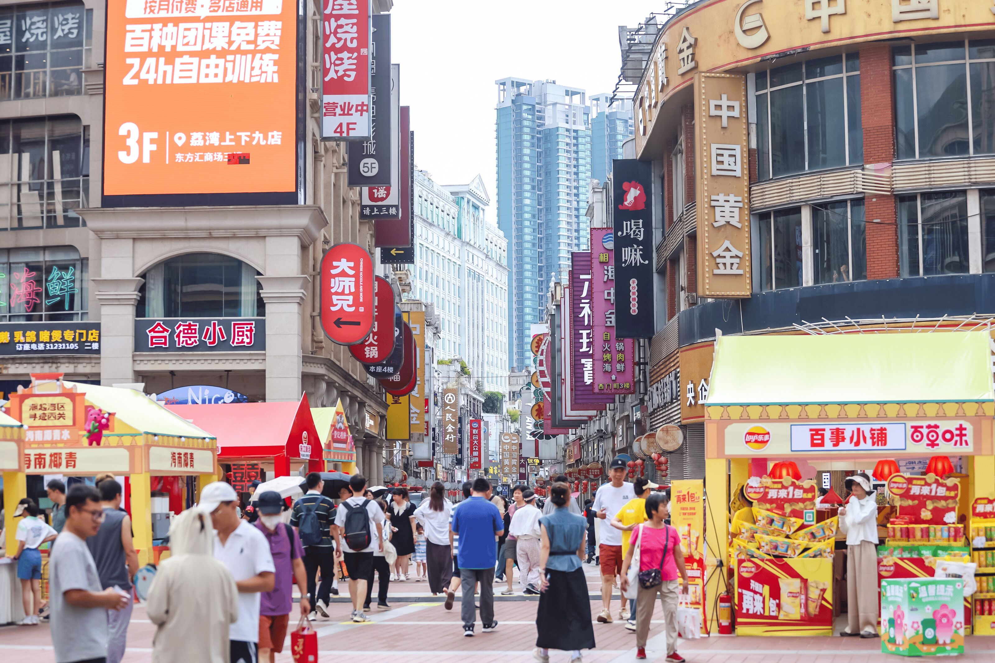 A busy street with various shops and signs, including a prominent orange advertisement.