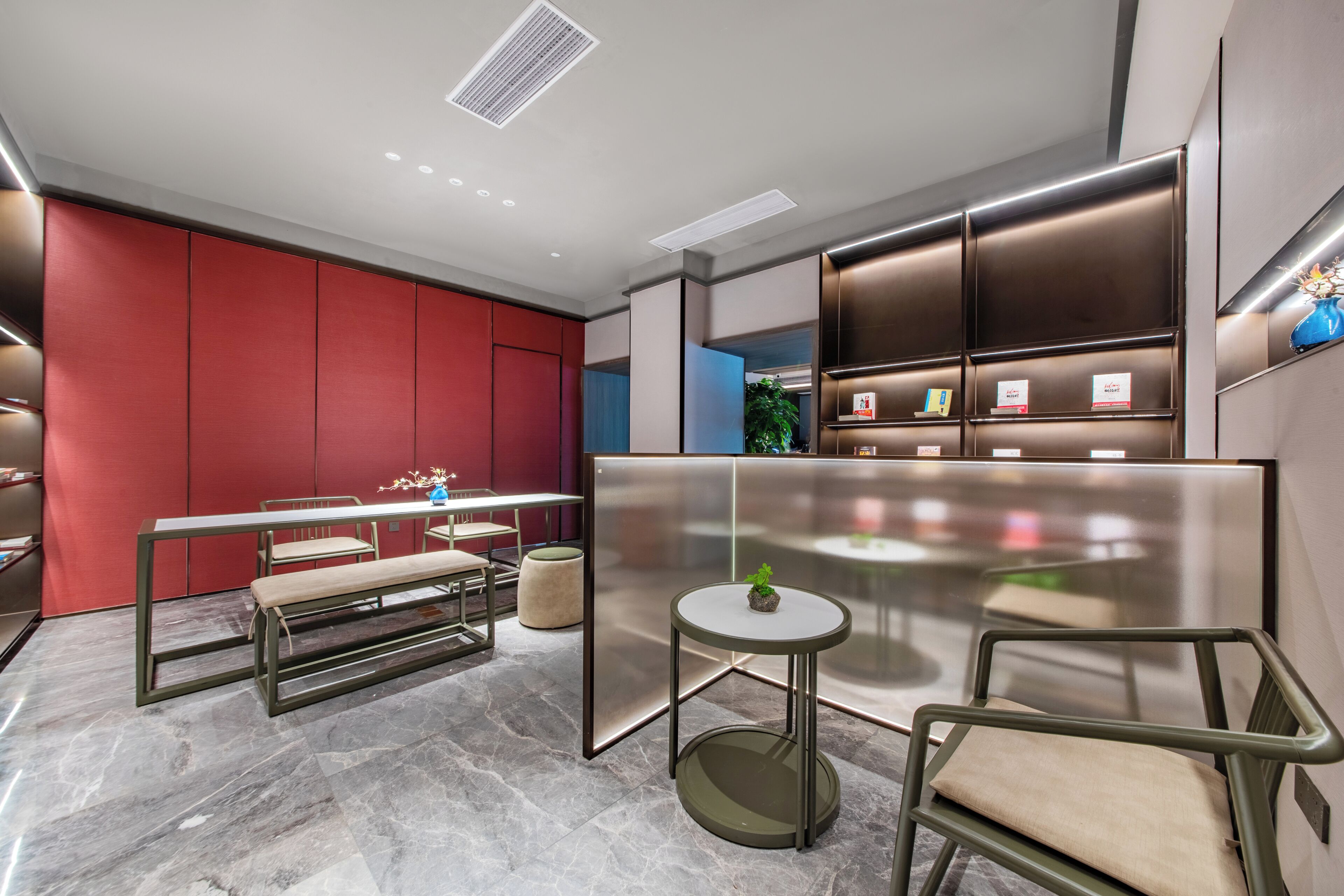 A modern interior with a red accent wall, a central table, and a seating area.