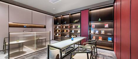 A modern library with a glass partition, a marble floor, and bookshelves with books and decorative items.