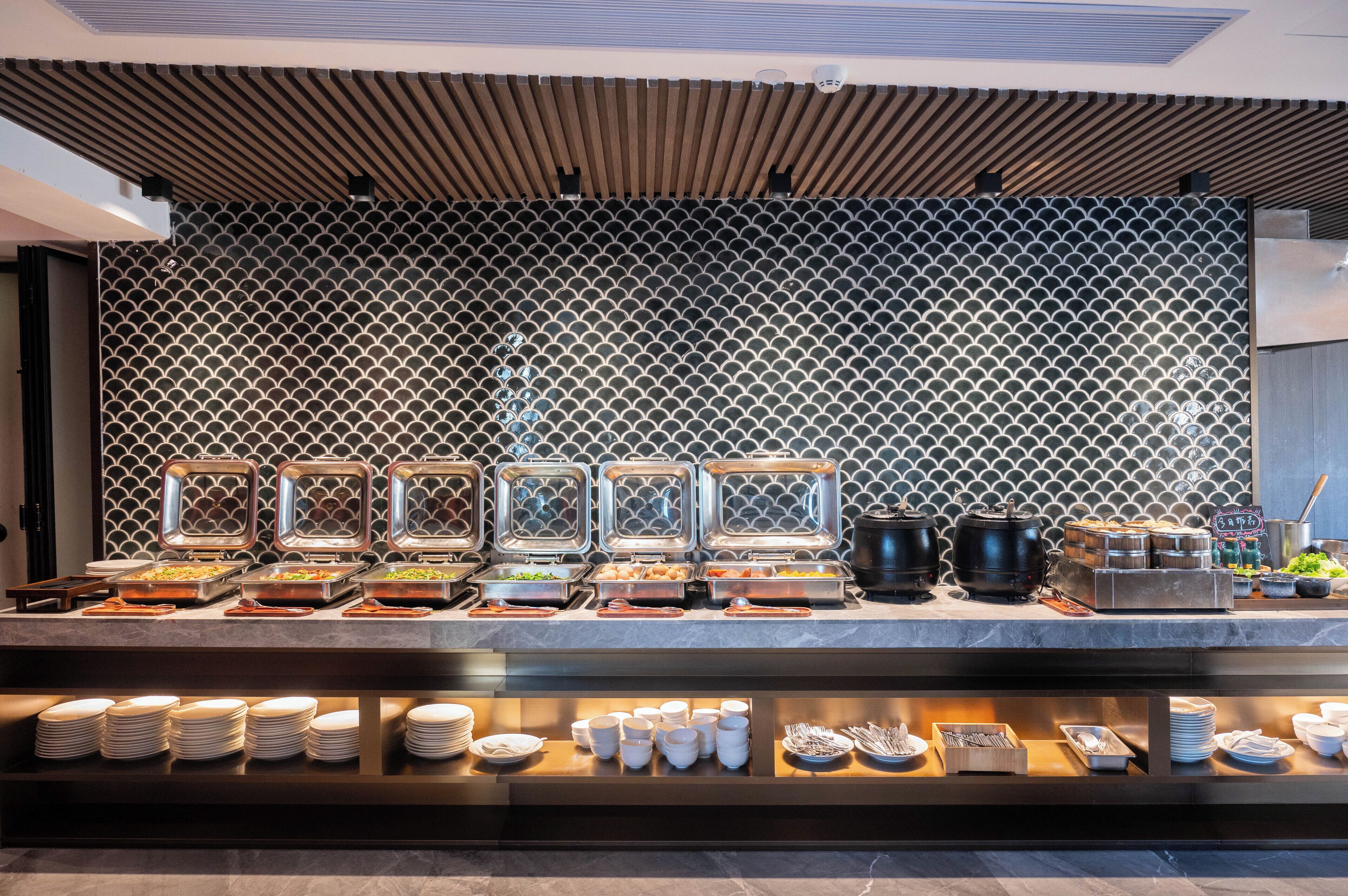 A buffet setup with various food items and serving utensils.