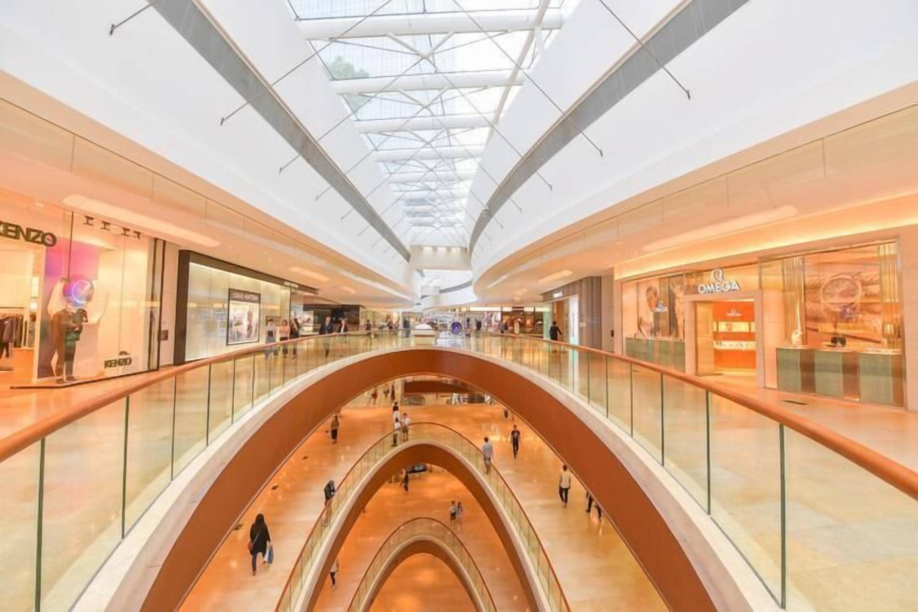 A multi-level shopping mall with glass railings and a central atrium.