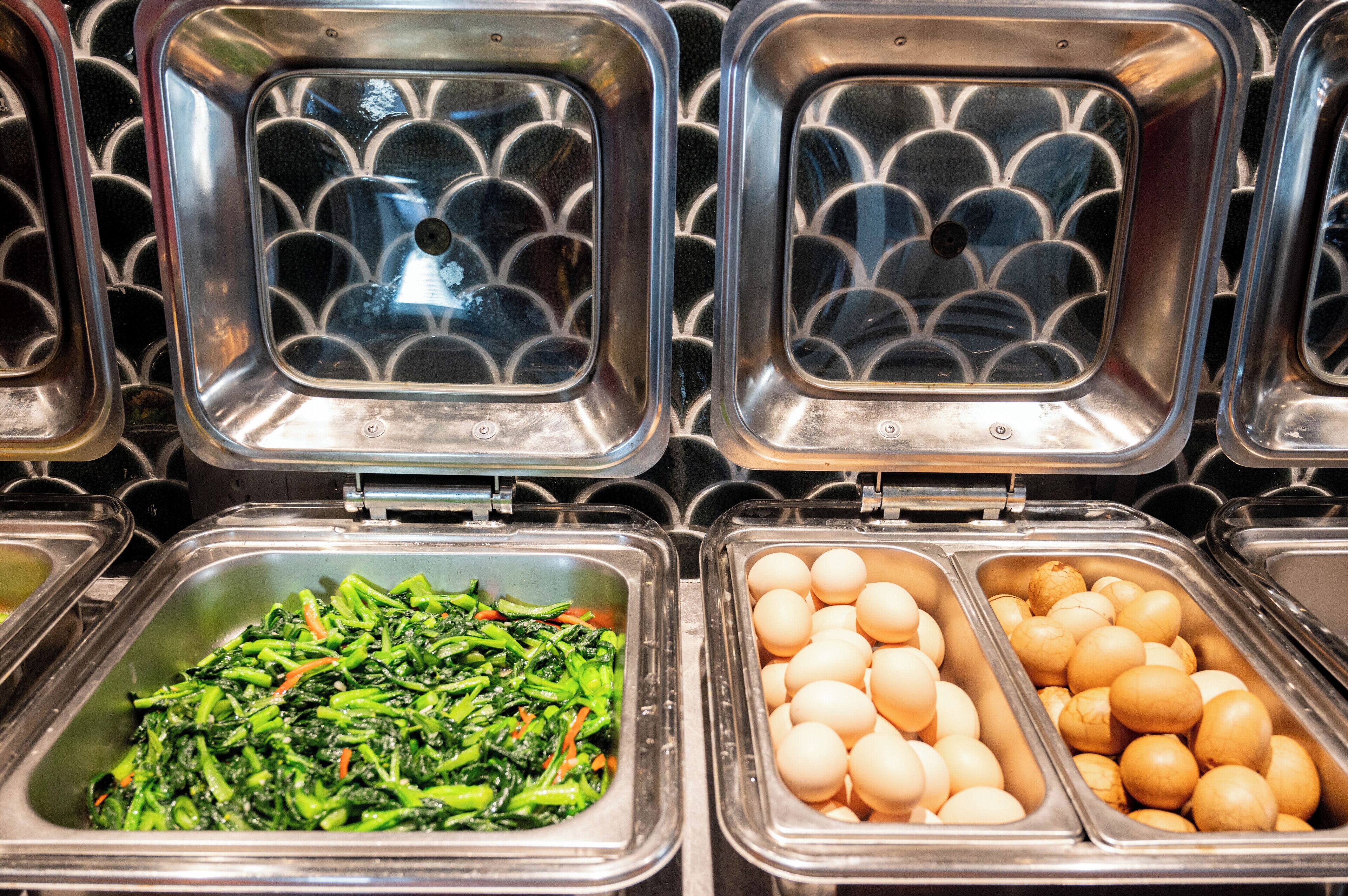 A buffet with various food items including greens and eggs.