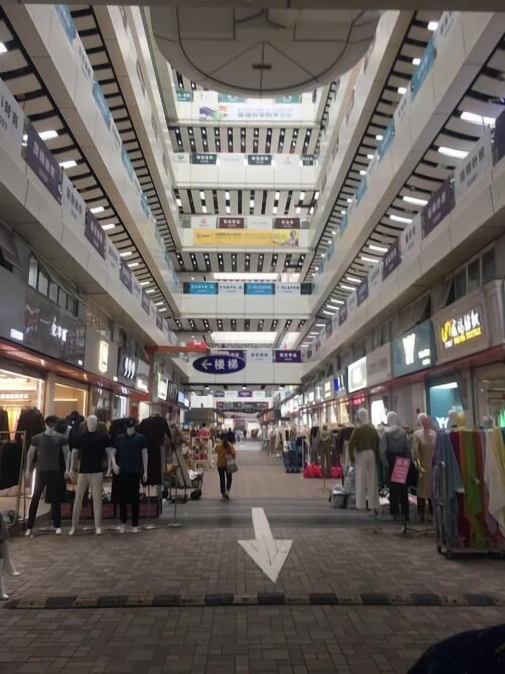 A multi-level shopping mall with various stores and a central walkway.