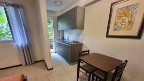 A dining area with a table and chairs, a kitchen in the background, and a framed artwork on the wall. - Day & Night Accommodations (Daanbantayan)