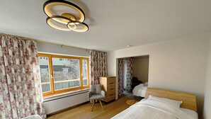 Ein Schlafzimmer mit zwei Betten, einer Holzkommode, einem Stuhl und einer Heizung.