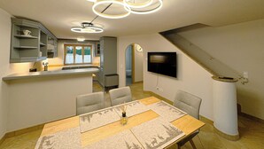 Eine moderne Küche mit eingebauten Geräten, ein Essbereich mit Holztisch und -stühlen sowie eine Treppe, die zu einer weiteren Ebene führt.