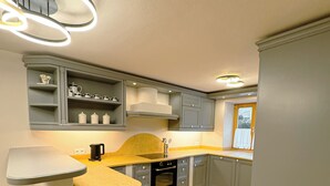 Eine moderne Küche mit grauen Schränken, einem eingebauten Ofen und einer Arbeitsplatte mit Spüle.