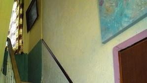 A staircase with wooden steps and white railings, a door with a purple frame, and a wall with a painting.