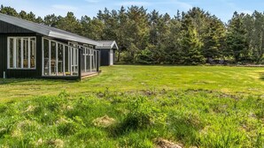 Une maison moderne dotée de grandes baies vitrées et d’une vaste pelouse.