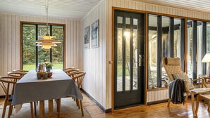 Un espace repas comprenant une table et des chaises, une grande fenêtre et une porte donnant sur l’extérieur.