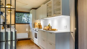 Une cuisine moderne avec des meubles blancs, un plan de travail en bois et une fenêtre qui laisse entrer la lumière naturelle.