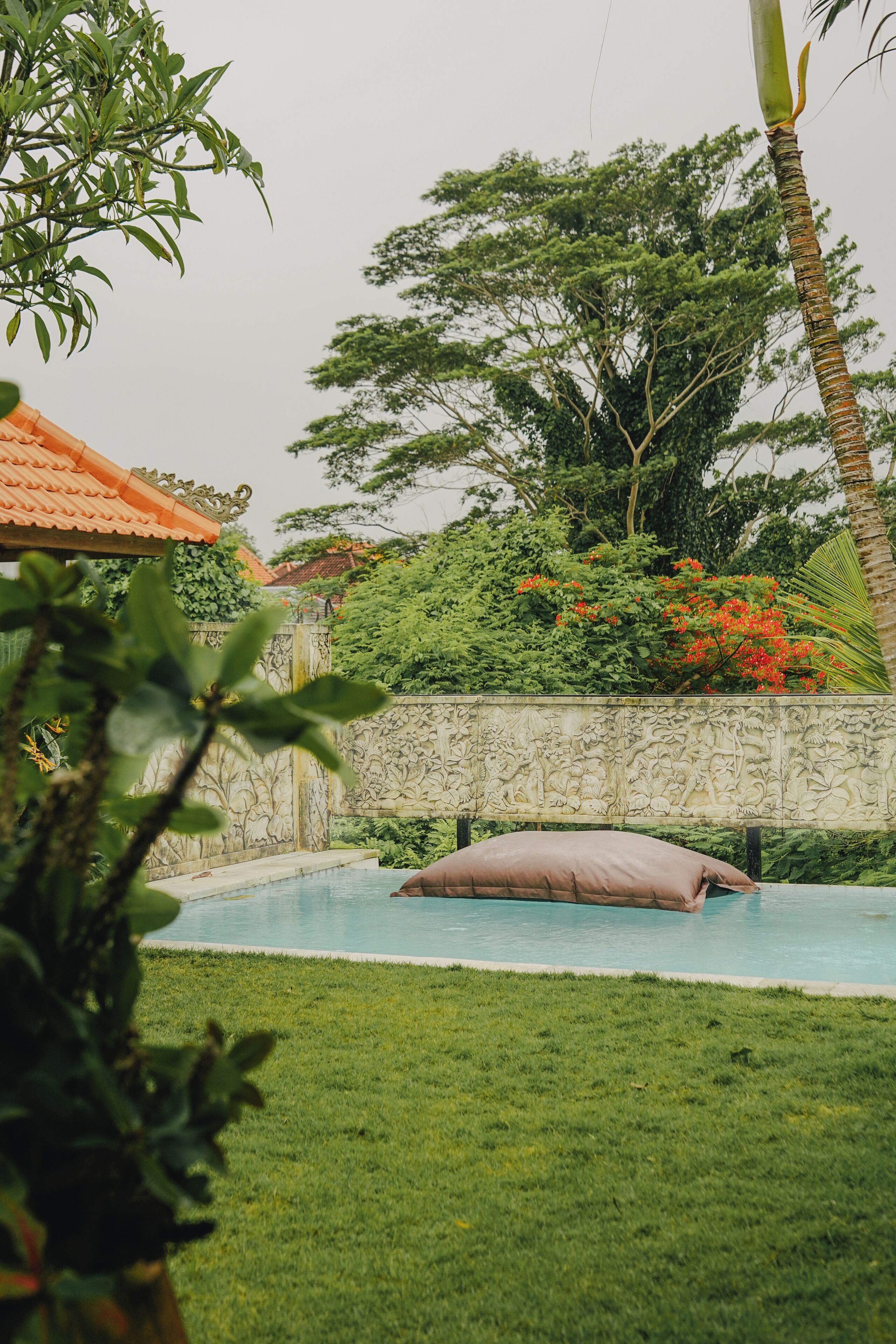 A swimming pool with a stone wall and lush greenery in the background.