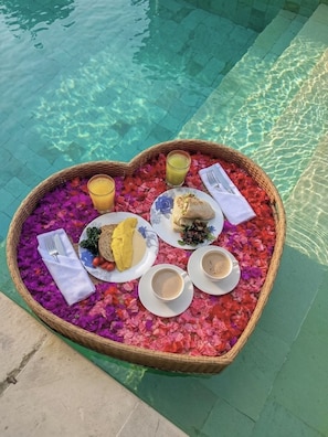 A heart-shaped tray with breakfast items by a pool. - Tropical Villa Indah - Private Jungle Oasis with Pool & Views (Ungasan)