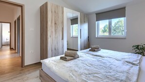 Un dormitorio con cama, armario de madera, espejo y ventana.