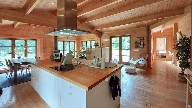 Une cabine spacieuse dotée d’un grand espace repas en bois, d’un îlot central dans la cuisine et d’un salon confortable avec une cheminée.