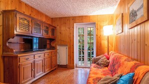 Ein Holzinnenraum mit einer Küche, einem Sofa und einer Tür, die nach draußen führt.