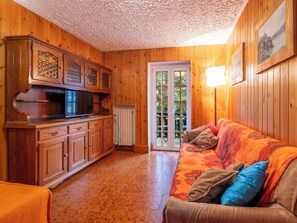 A wooden interior with a kitchen, a sofa, and a door leading outside.