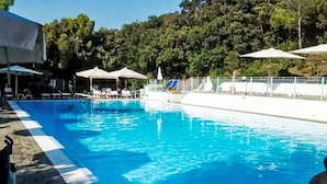 Ein Swimmingpool mit klarem, blauem Wasser, umgeben von Sonnenschirmen und Liegestühlen.