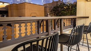 A terrace with a view of the Burj Khalifa at night, featuring a railing and two chairs.