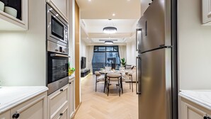 A modern kitchen with built-in appliances, a dining area with a round table, and a view of the city through large windows.