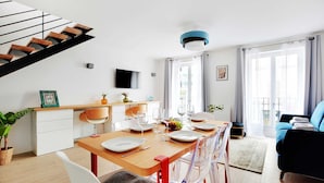 A modern living room with a dining area, a staircase, and a balcony. - Beautiful Apartment- 3br/10p - Montparnasse (Paris)
