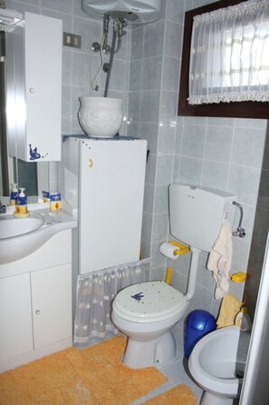 A compact bathroom with a toilet, bidet, and sink.
