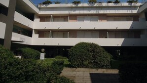 A multi-story building with balconies, a central courtyard, and a sign indicating a public space. - Apartment with rooftop swimming pool (Bibione)